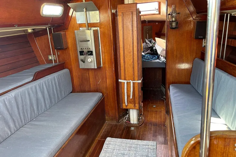 Slide: The Image of 1982 Ericson 33 sailboat interior with wooden paneling and blue cushioned seating. - 17