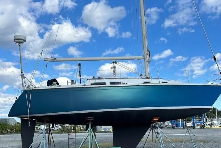 Slide: The Image of 1982 Ericson 33 sailboat on stands, blue hull, clear sky background. - 2