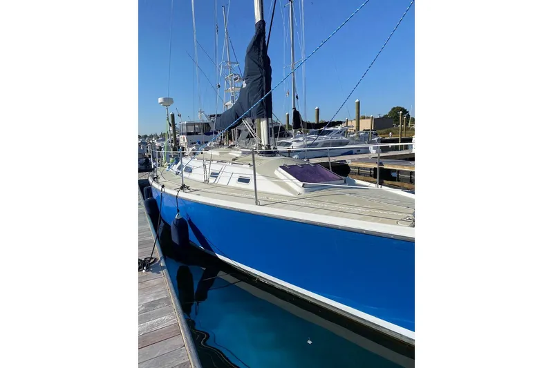 Slide: The Image of 1982 Ericson 33 sailboat docked, featuring a sleek blue hull and white deck. - 23