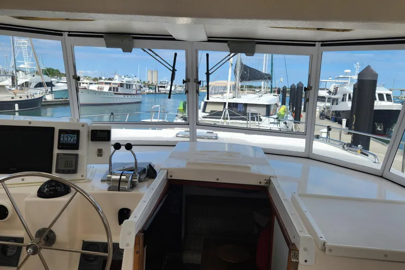 Slide: The Image of 2005 Endeavour 44 TrawlerCat helm view with marina background, showcasing navigation instruments. - 43