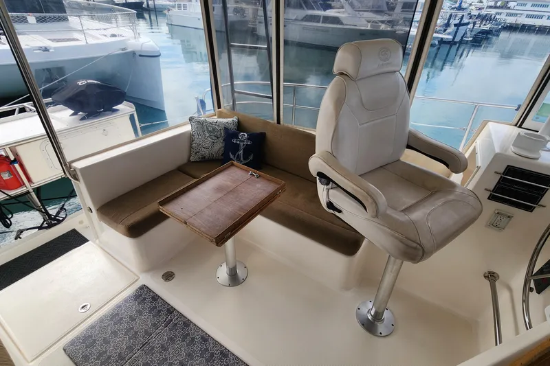 Slide: The Image of Interior of 2005 Endeavour 44 TrawlerCat with helm seat, sofa, and table in marina setting. - 46