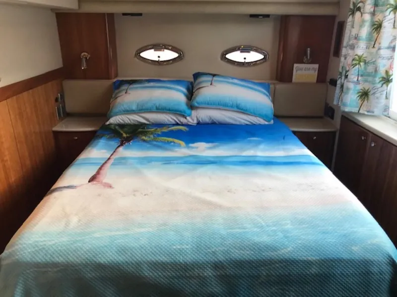Slide: The Image of 2004 Meridian 459 Motoryacht bedroom with beach-themed bedding and porthole windows. - 34