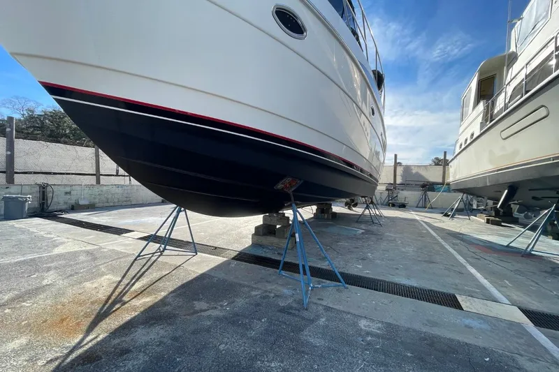 Slide: The Image of 2004 Meridian 459 Motoryacht on stands in a boatyard under clear blue sky. - 55