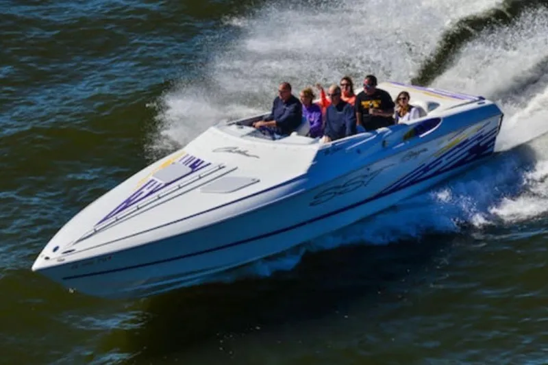 The Image of 1999 Baja 33 Outlaw speedboat cruising on water with passengers onboard. - 1
