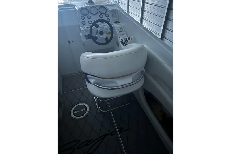 Slide: The Image of 1999 Baja 33 Outlaw boat cockpit with steering wheel and white seating. - 12