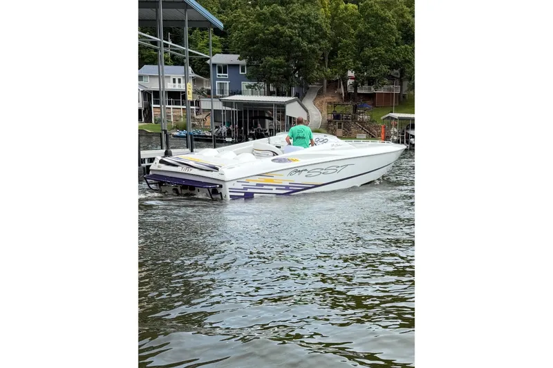 Slide: The Image of 1999 Baja 33 Outlaw boat on water near dock, surrounded by trees and houses. - 3