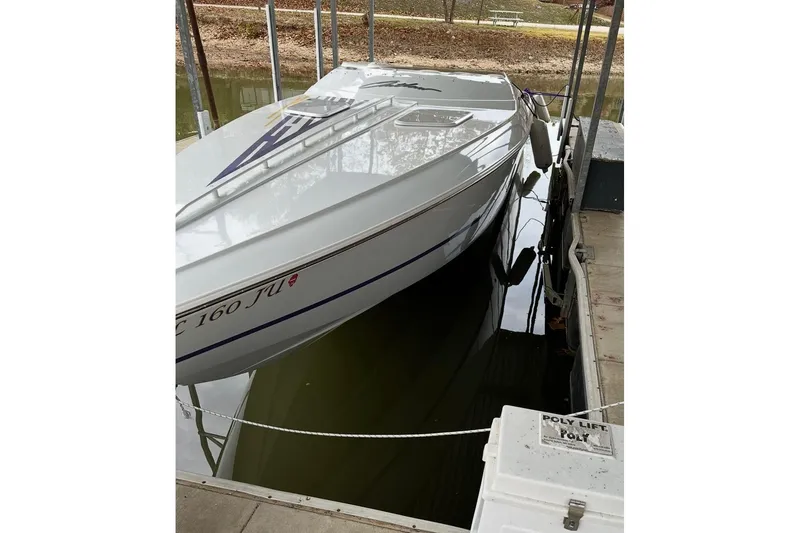 Slide: The Image of 1999 Baja 33 Outlaw boat docked on a lift in calm waters. - 5