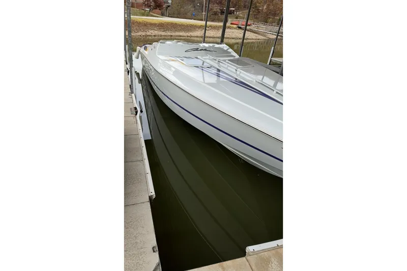 Slide: The Image of 1999 Baja 33 Outlaw boat docked, sleek white design with blue accents. - 6