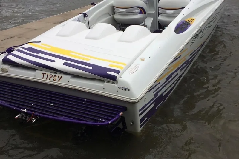 Slide: The Image of 1999 Baja 33 Outlaw speedboat with vibrant purple and yellow design, docked at a pier. - 7