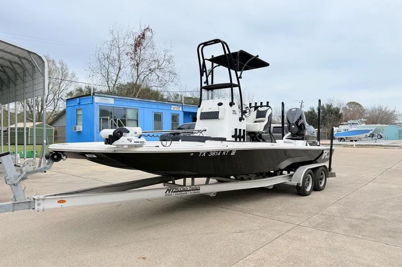 The Image of 2023 Tidewater 25 TPC Raptor boat on trailer, parked outdoors near blue building. - 1