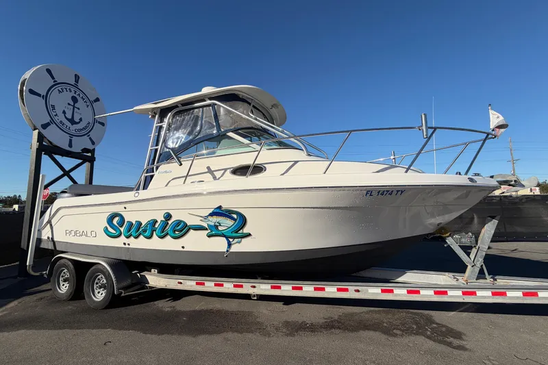 The Image of 2017 Robalo R265 Walkaround boat on trailer, named "Susie-Q," at a dealership. - 0