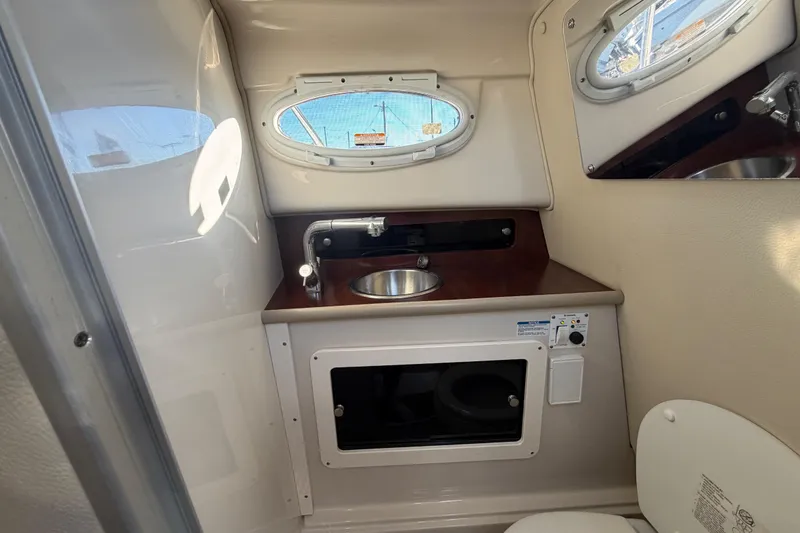 Slide: The Image of 2017 Robalo R265 Walkaround boat interior with sink, toilet, and porthole windows. - 46