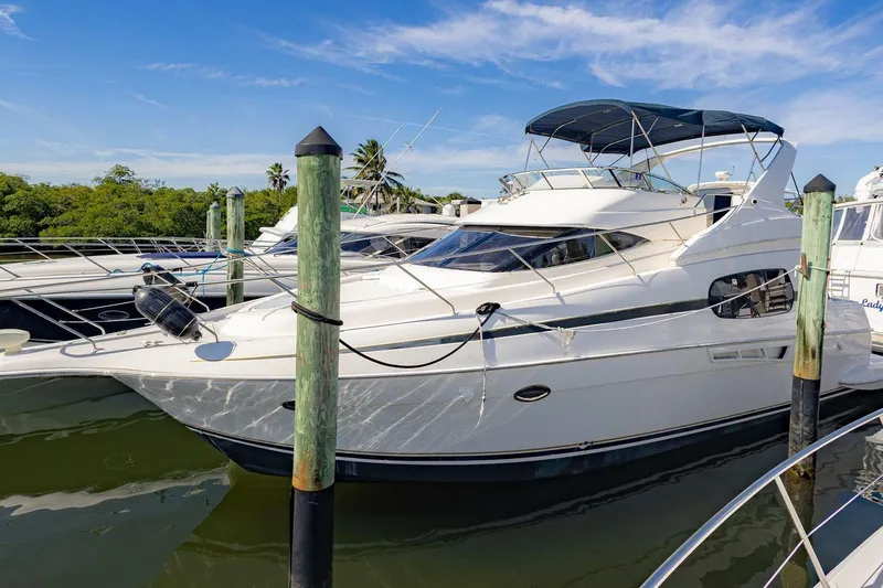 The Image of 2001 Silverton 410 Sport Bridge yacht docked at marina under clear blue sky. - 1