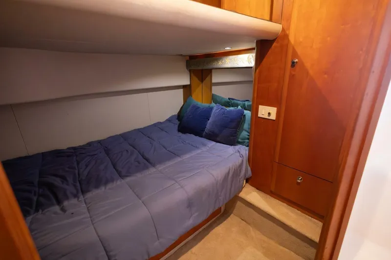 Slide: The Image of Cozy cabin interior of 2001 Silverton 410 Sport Bridge with plush bedding and wooden cabinetry. - 13