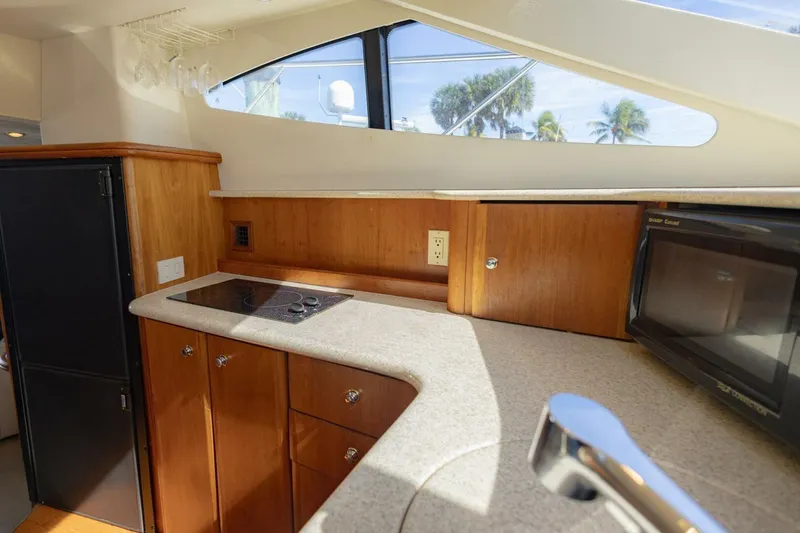 Slide: The Image of 2001 Silverton 410 Sport Bridge yacht kitchen with stove, microwave, and wooden cabinetry. - 25
