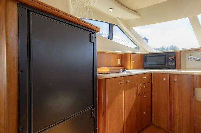 Slide: The Image of 2001 Silverton 410 Sport Bridge yacht kitchen with wood cabinets, microwave, and refrigerator. - 31