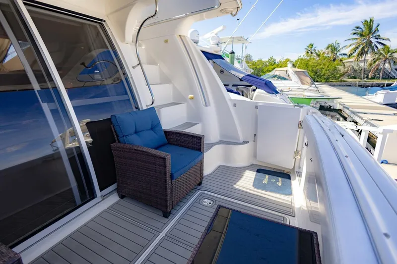 Slide: The Image of 2001 Silverton 410 Sport Bridge yacht deck with wicker chair, docked near palm trees. - 34