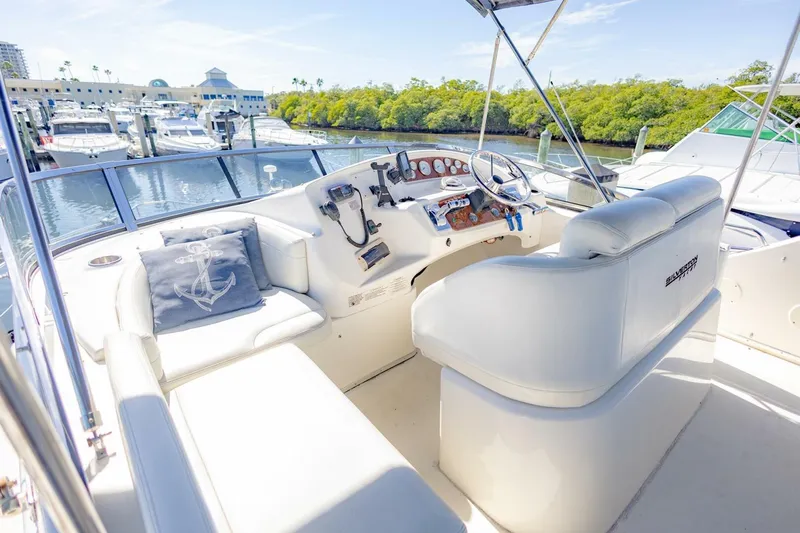 Slide: The Image of 2001 Silverton 410 Sport Bridge yacht helm with white seating and marina view. - 38
