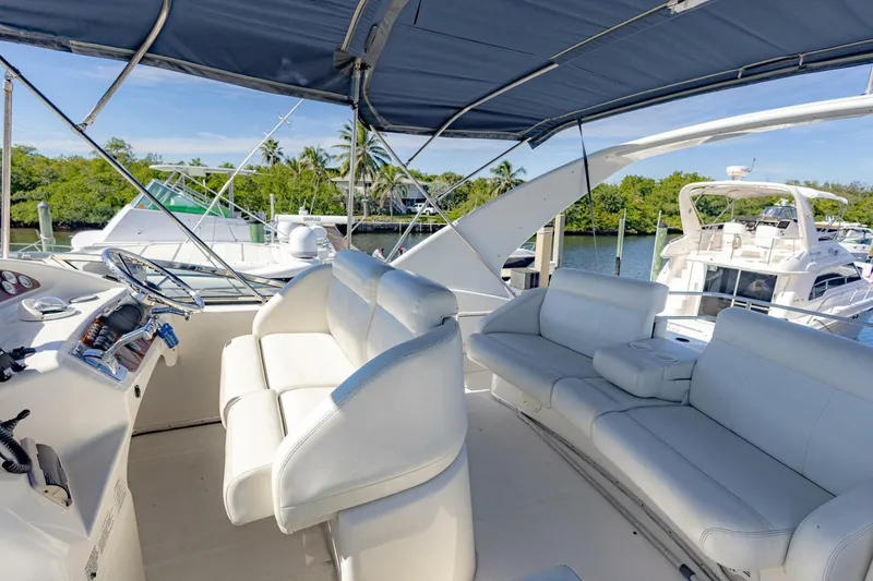 Slide: The Image of 2001 Silverton 410 Sport Bridge yacht interior with white seating and helm, docked at marina. - 41