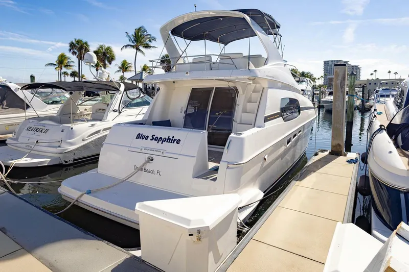 Slide: The Image of 2001 Silverton 410 Sport Bridge yacht docked at marina, labeled "Blue Sapphire," in sunny setting. - 55
