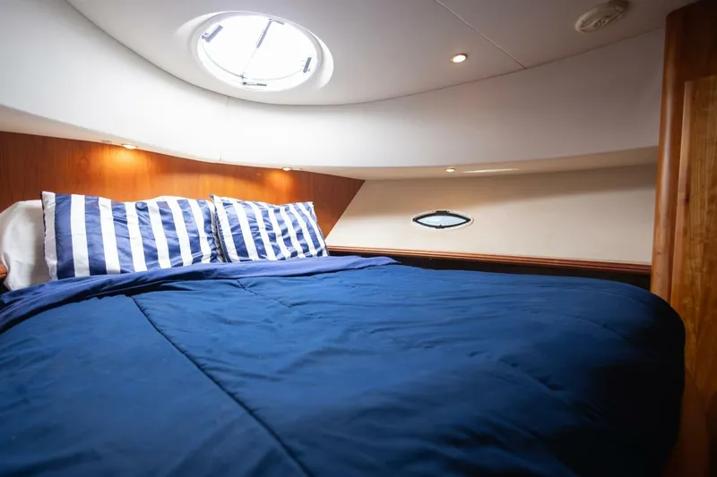 Slide: The Image of Cozy cabin interior of 2001 Silverton 410 Sport Bridge with blue bedding and striped pillows. - 6