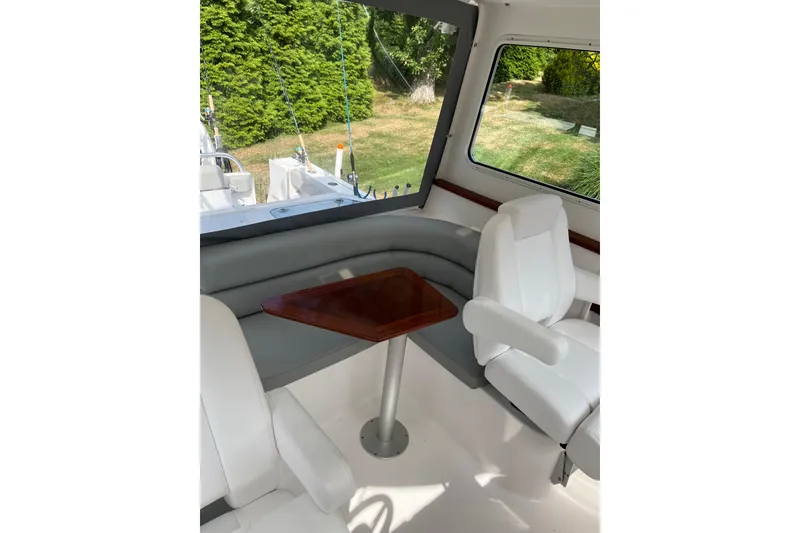 Slide: The Image of Interior of 2025 NorthCoast 285 HT boat with white seating and wooden table. - 9