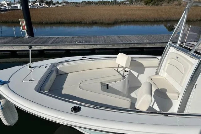 Slide: The Image of 2024 Sea Hunt Ultra 229 boat with sleek seating, docked by calm waters. - 14