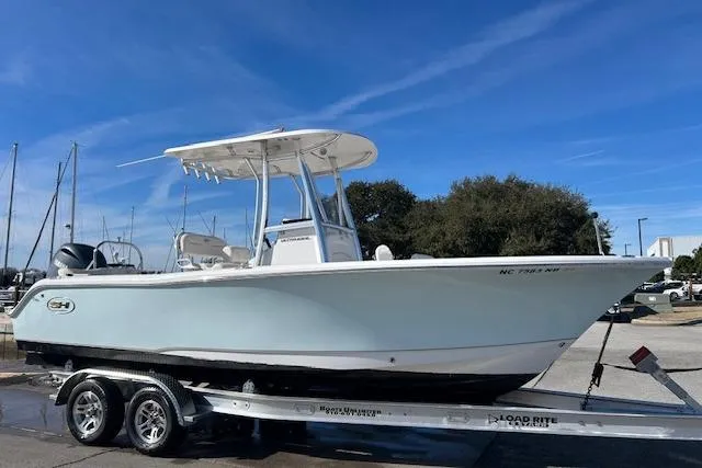 Slide: The Image of 2024 Sea Hunt Ultra 229 boat on trailer, parked outdoors under clear blue sky. - 15