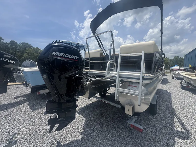 Slide: The Image of A 2026 Lowe LS Walk Thru 210 pontoon boat with a Mercury outboard motor on a gravel lot. - 8