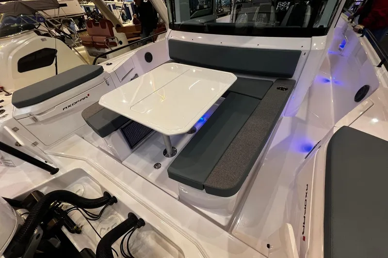 Slide: The Image of 2026 Axopar 37 XC Cross Cabin interior with seating and table, illuminated by blue lights. - 23