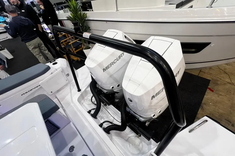 Slide: The Image of 2026 Axopar 37 XC Cross Cabin with dual Mercury outboard engines at a boat show. - 37