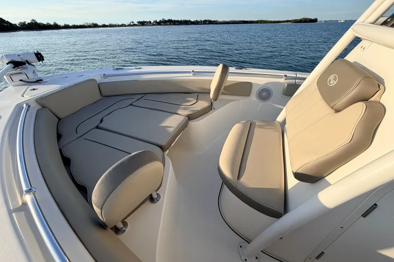 Slide: The Image of 2023 Key West 219 FS boat interior with cushioned seating, on calm water. - 14