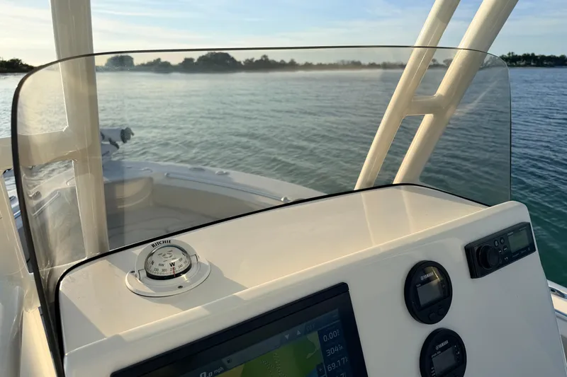 Slide: The Image of 2023 Key West 219 FS boat dashboard with compass and digital displays on calm water. - 27
