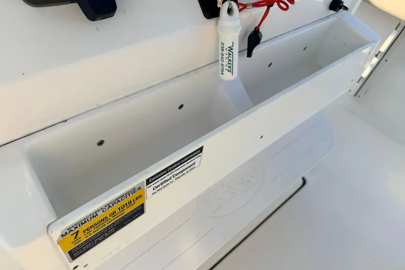 Slide: The Image of 2023 Key West 219 FS boat interior with storage compartment and safety label. - 34