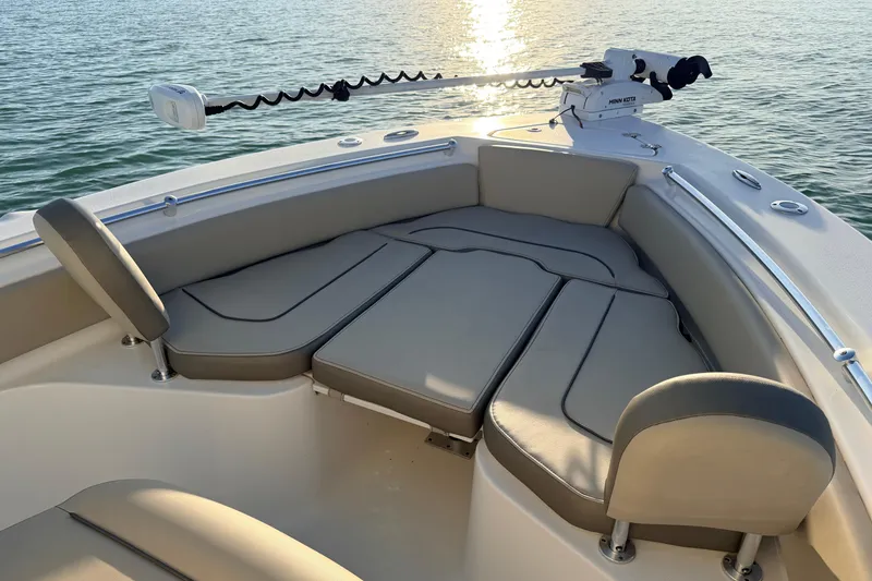 Slide: The Image of 2023 Key West 219 FS boat interior with cushioned seating and trolling motor on calm water. - 5
