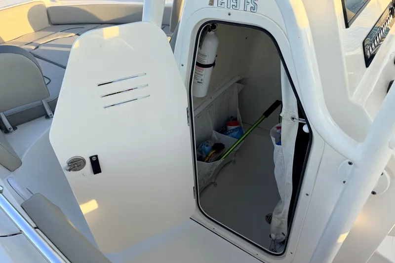 Slide: The Image of 2023 Key West 219 FS boat storage compartment with open door and visible equipment. - 62