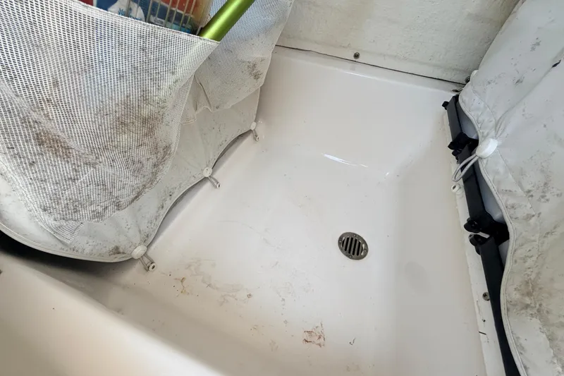 Slide: The Image of 2023 Key West 219 FS boat storage compartment with mesh netting and drain. - 64