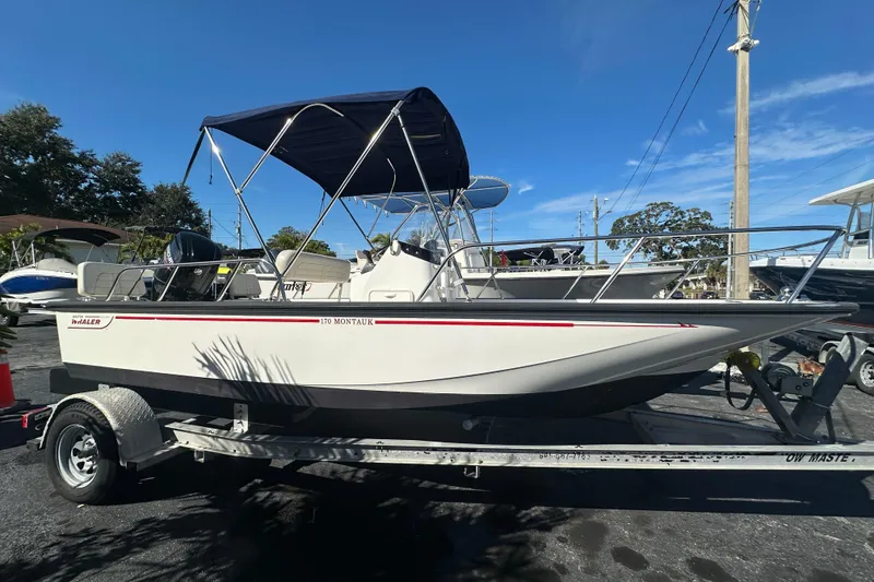 The Image of 2021 Boston Whaler 170 Montauk boat on trailer with canopy, parked outdoors. - 1