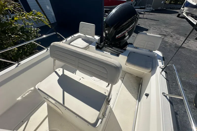 Slide: The Image of 2021 Boston Whaler 170 Montauk boat interior with Mercury engine, featuring seating and railings. - 10