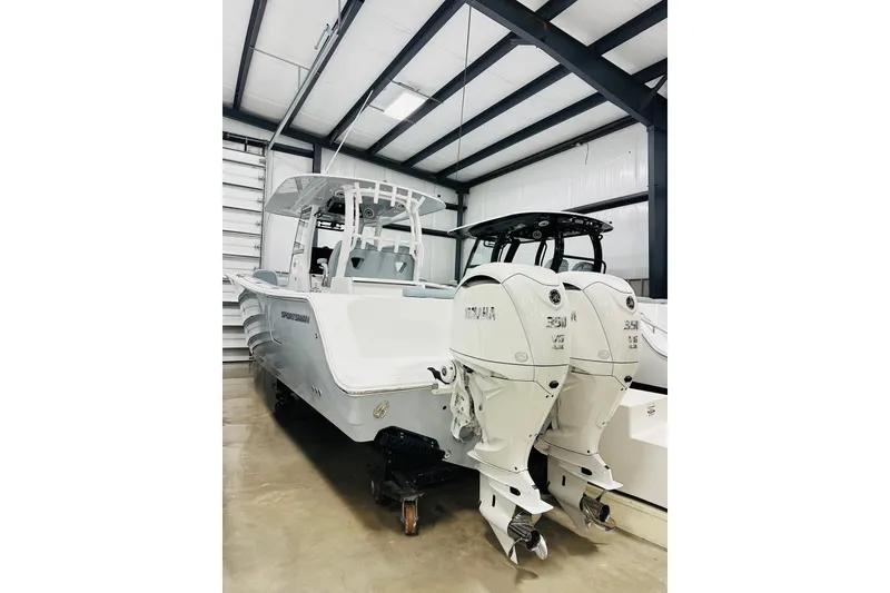 The Image of 2026 Sportsman Open 302 Center Console boat with dual Yamaha engines in a storage facility. - 1