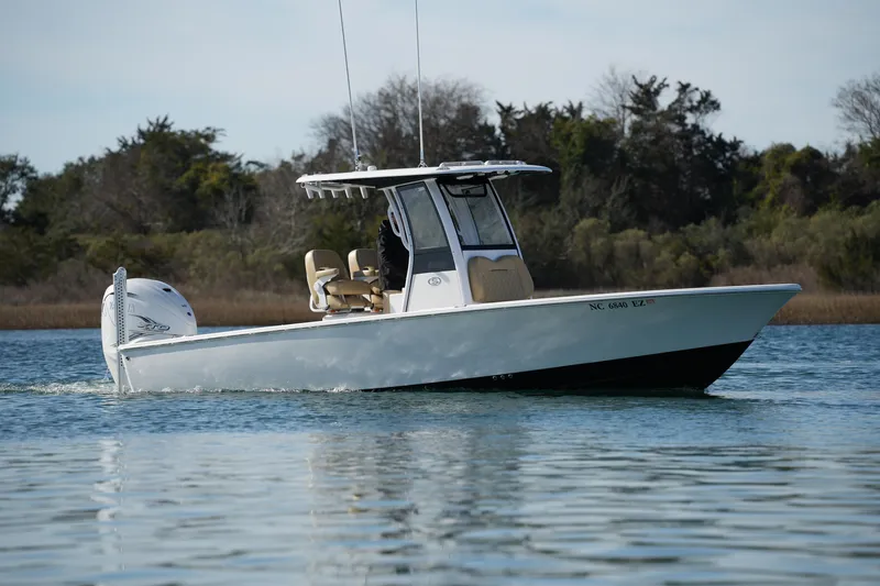 The Image of 2023 Sportsman Masters 267 Bay Boat cruising on calm water, surrounded by trees. - 0