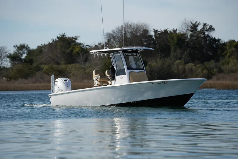 Slide: The Image of 2023 Sportsman Masters 267 Bay Boat cruising on calm water with trees in the background. - 1