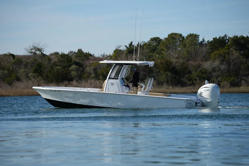 Slide: The Image of 2023 Sportsman Masters 267 Bay Boat cruising on calm water, surrounded by trees. - 10