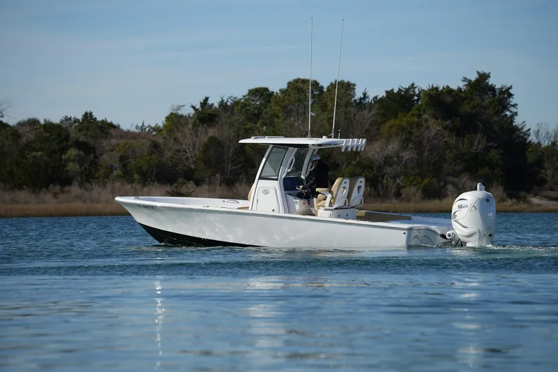 Slide: The Image of 2023 Sportsman Masters 267 Bay Boat cruising on calm water, surrounded by trees. - 11