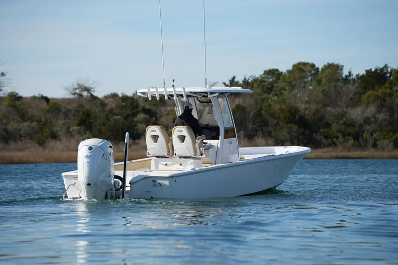 Slide: The Image of 2023 Sportsman Masters 267 Bay Boat cruising on calm water, surrounded by trees. - 14