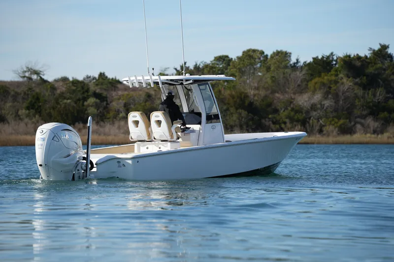 Slide: The Image of 2023 Sportsman Masters 267 Bay Boat cruising on calm water, surrounded by trees. - 15