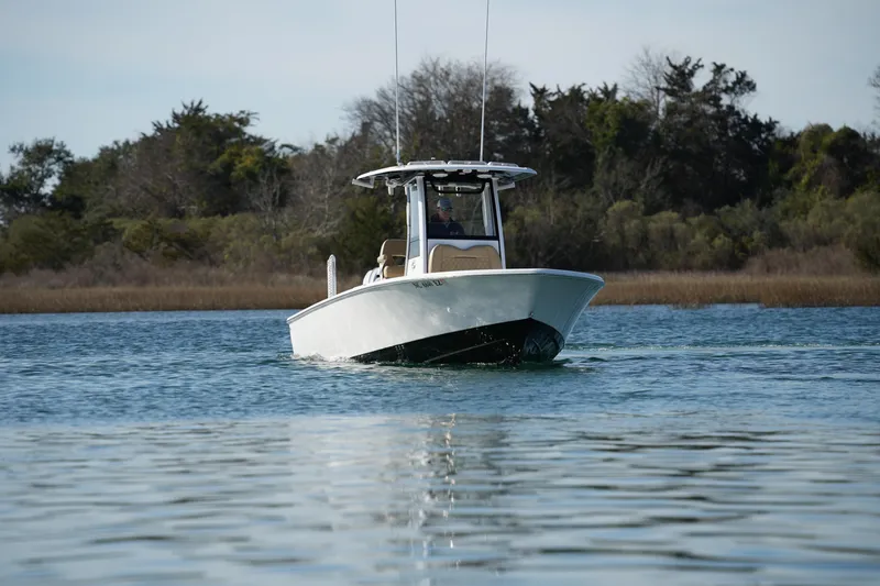 Slide: The Image of 2023 Sportsman Masters 267 Bay Boat cruising on calm water near a wooded shoreline. - 3