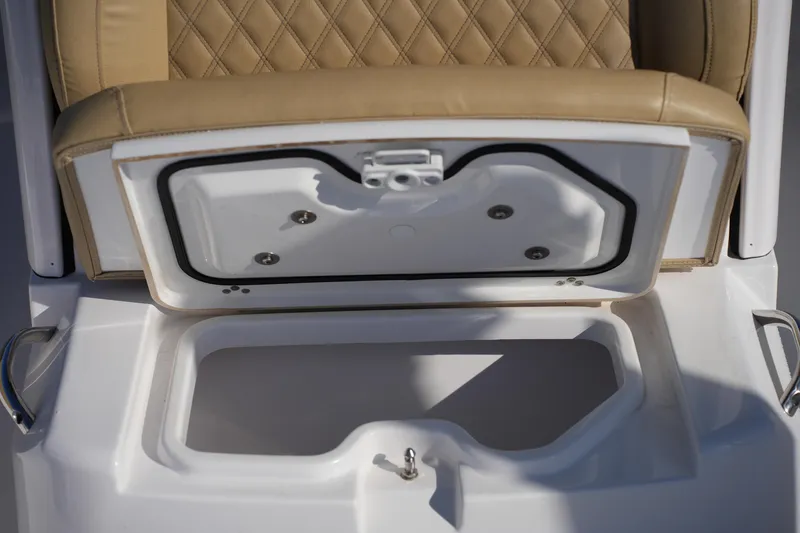 Slide: The Image of 2023 Sportsman Masters 267 Bay Boat seat storage compartment with tan upholstery and white interior. - 39