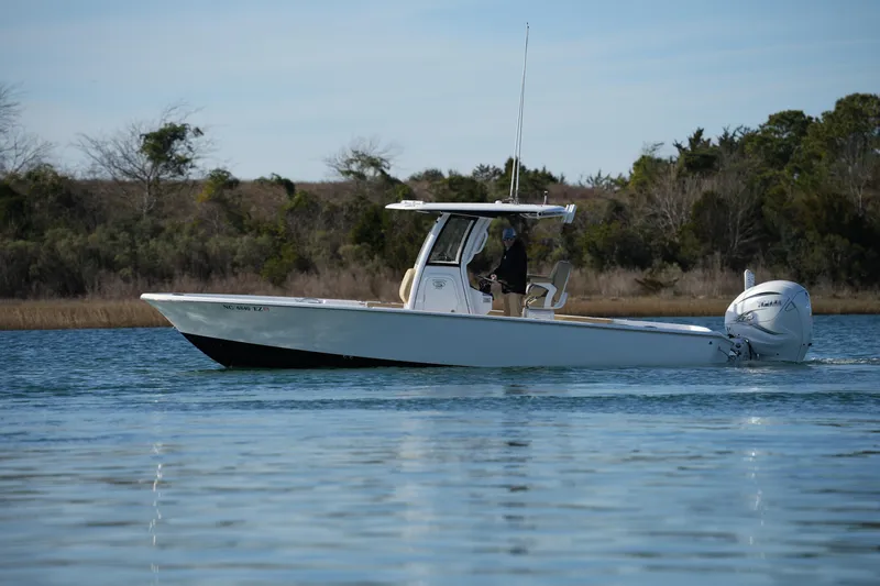 Slide: The Image of 2023 Sportsman Masters 267 Bay Boat cruising on calm water near a wooded shoreline. - 9