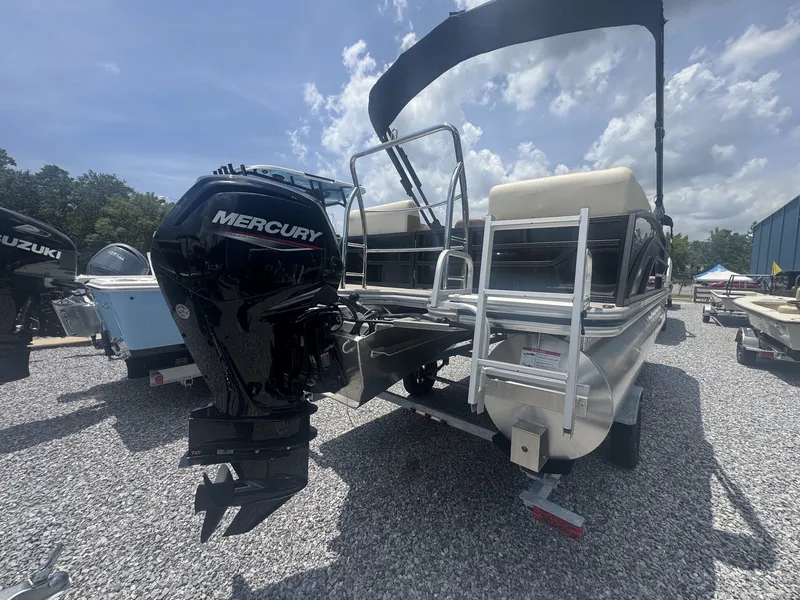 Slide: The Image of A 2026 Lowe LS Walk Thru 210 pontoon boat with a Mercury outboard motor, parked on gravel. - 8